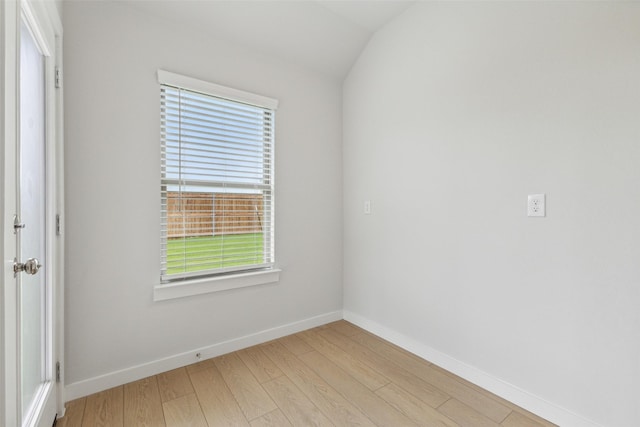 empty room featuring vaulted ceiling, light wood-style flooring, and baseboards