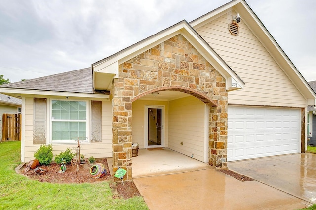 view of front of property with stone siding, a shingled roof, driveway, and fence