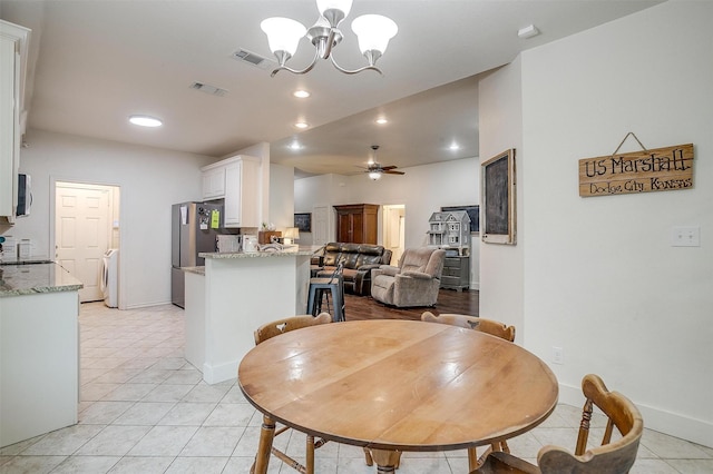 dining area featuring light tile patterned floors, washer / clothes dryer, visible vents, and ceiling fan with notable chandelier
