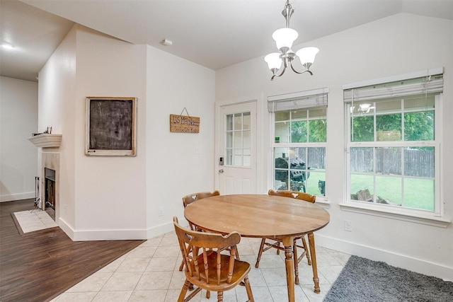 dining space with a chandelier, baseboards, light tile patterned floors, and a tiled fireplace