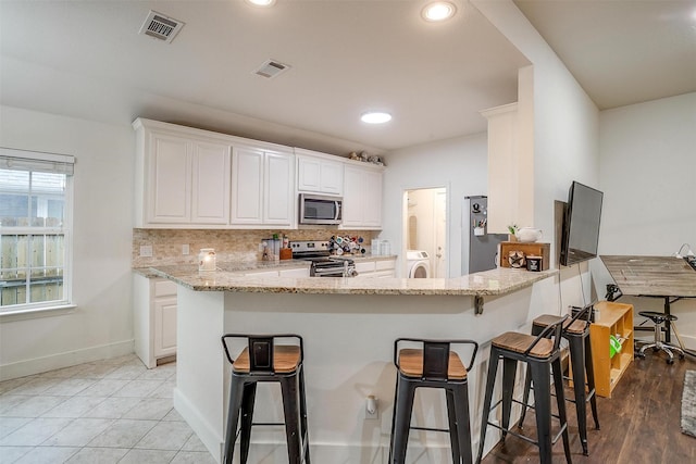 kitchen with white cabinets, stainless steel appliances, baseboards, and visible vents