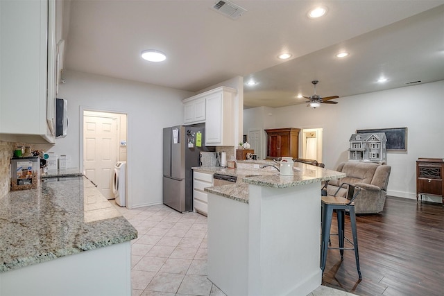 kitchen with a peninsula, a breakfast bar area, separate washer and dryer, stainless steel appliances, and visible vents