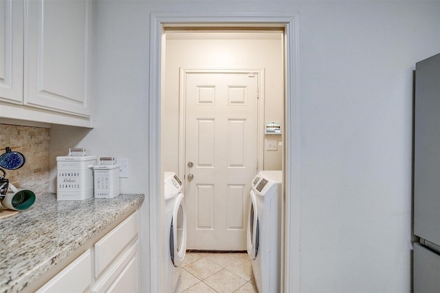 laundry area with light tile patterned floors, independent washer and dryer, and cabinet space