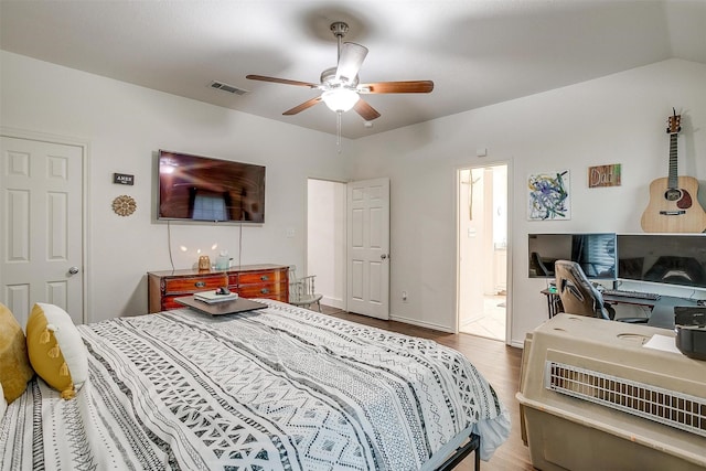 bedroom featuring wood finished floors, a ceiling fan, visible vents, baseboards, and ensuite bath
