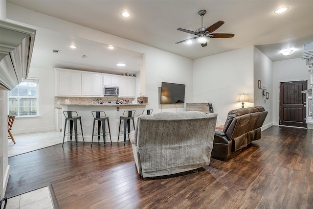 living area with dark wood-type flooring, baseboards, visible vents, ceiling fan, and recessed lighting