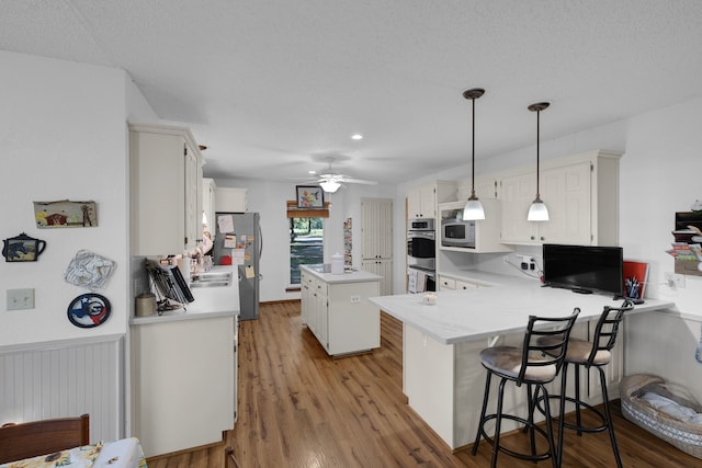 906 County Road 2770, Honey Grove, TX 75446 - kitchen with a ceiling fan, a kitchen island, light countertops, white cabinets, and appliances with stainless steel finishes