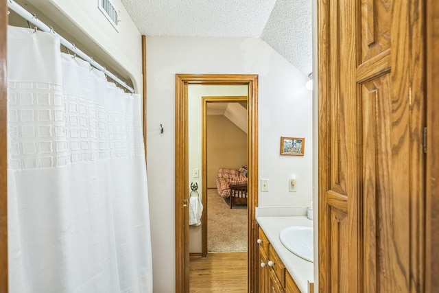 906 County Road 2770, Honey Grove, TX 75446 - full bath featuring wood finished floors, vanity, a textured ceiling, visible vents, and vaulted ceiling