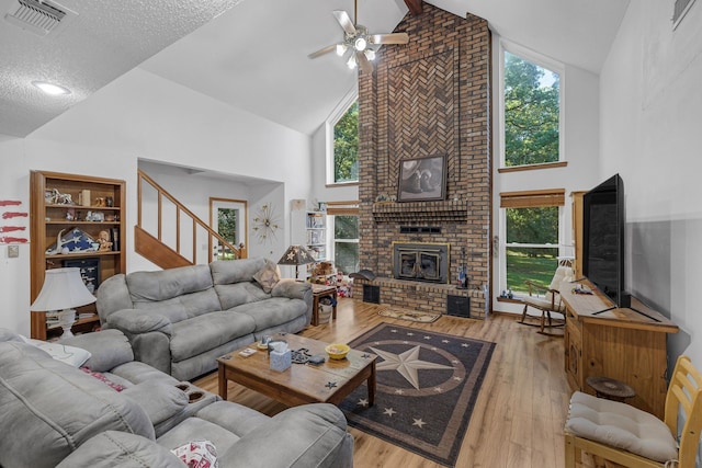 906 County Road 2770, Honey Grove, TX 75446 - living room with hardwood / wood-style flooring, high vaulted ceiling, visible vents, ceiling fan, and a brick fireplace