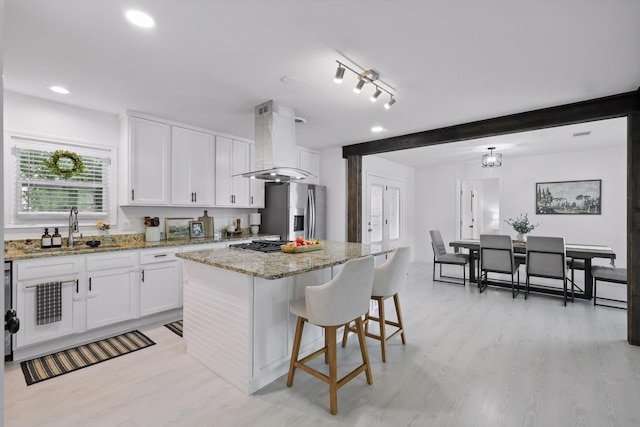 1718 Heather Rd, Gainesville, TX 76240 - kitchen with stainless steel refrigerator with ice dispenser, island range hood, a sink, a breakfast bar area, and white cabinetry