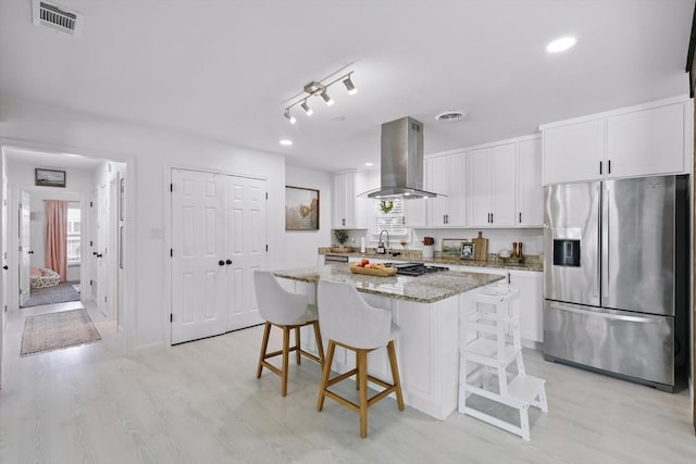 1718 Heather Rd, Gainesville, TX 76240 - kitchen with stainless steel fridge, island exhaust hood, white cabinetry, a kitchen island, and a kitchen breakfast bar