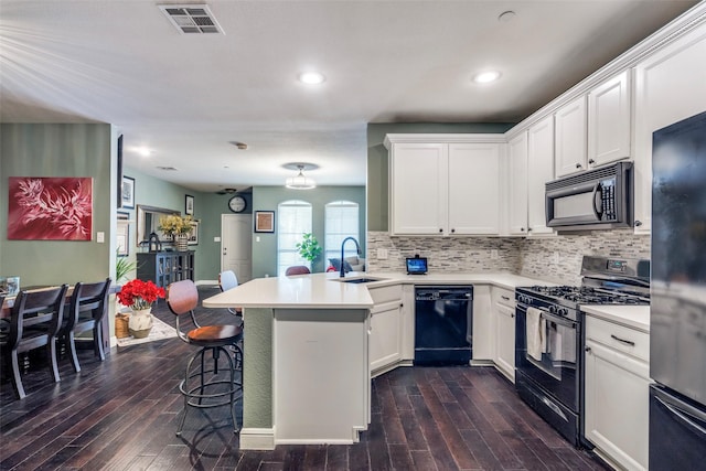 6844 Massa Ln, Frisco, TX 75034 - kitchen with visible vents, a sink, a peninsula, dark wood-type flooring, and black appliances