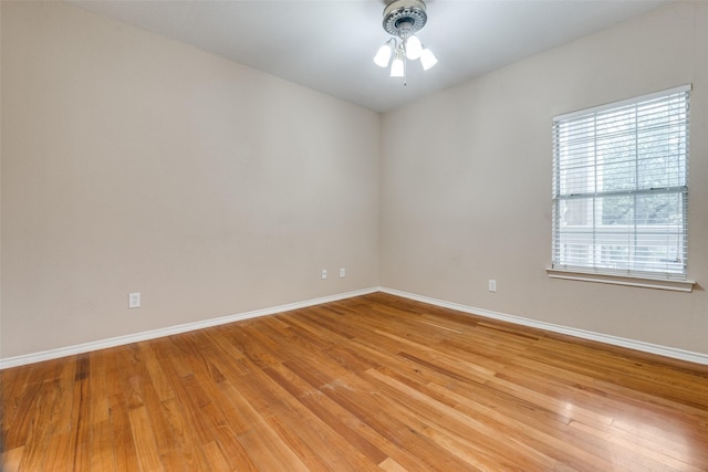 spare room featuring light wood finished floors, baseboards, and a ceiling fan