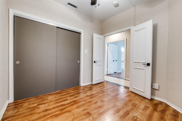 unfurnished bedroom featuring a closet, light wood-style flooring, and baseboards
