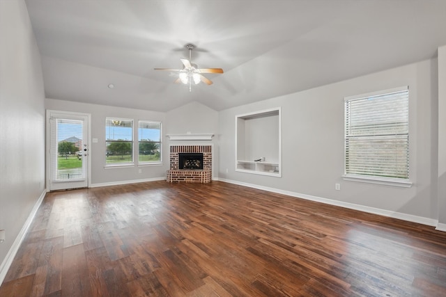 unfurnished living room featuring vaulted ceiling, dark wood-style flooring, a brick fireplace, a ceiling fan, and baseboards