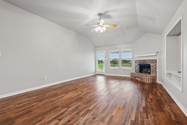 unfurnished living room featuring dark wood-style flooring, lofted ceiling, a brick fireplace, and a ceiling fan