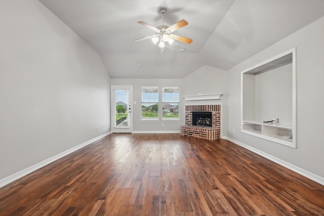 unfurnished living room with lofted ceiling, dark wood-type flooring, a brick fireplace, a ceiling fan, and baseboards