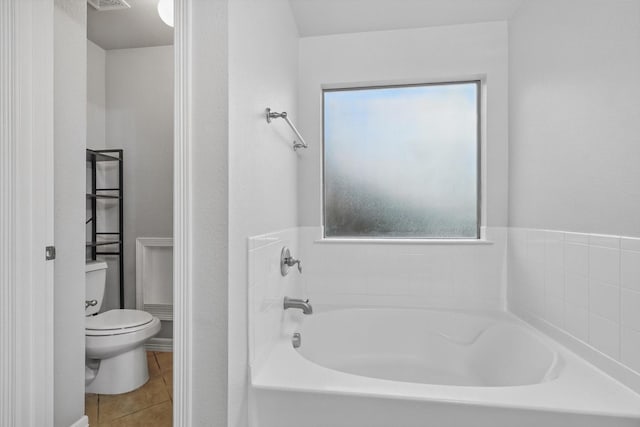 bathroom with toilet, tile patterned flooring, a garden tub, and visible vents