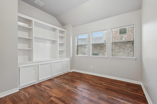 empty room with baseboards, lofted ceiling, visible vents, and dark wood-type flooring