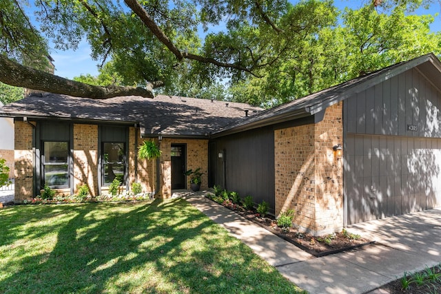 mid-century modern home featuring brick siding, a front yard, and a shingled roof