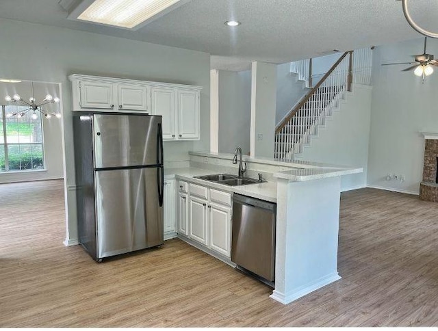 7636 Arbor Ridge Ct, Fort Worth, TX 76112 - kitchen with a peninsula, light wood-style flooring, a sink, stainless steel appliances, and white cabinets