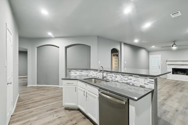 kitchen featuring a sink, dark countertops, stainless steel dishwasher, visible vents, and arched walkways