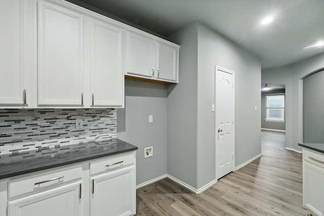 kitchen featuring tasteful backsplash, white cabinetry, baseboards, dark countertops, and light wood-style floors