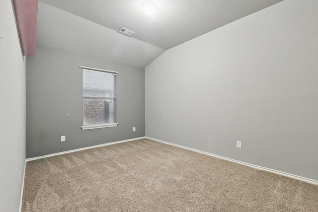 unfurnished room with baseboards, visible vents, carpet floors, and vaulted ceiling