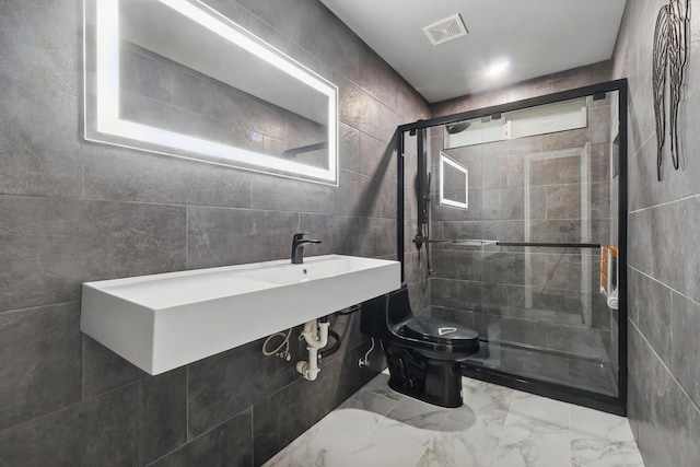 bathroom with toilet, tile walls, visible vents, a shower stall, and marble finish floor
