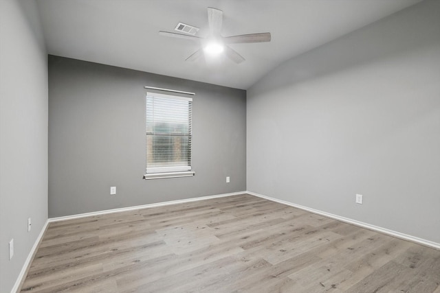 unfurnished room with lofted ceiling, wood finished floors, visible vents, a ceiling fan, and baseboards