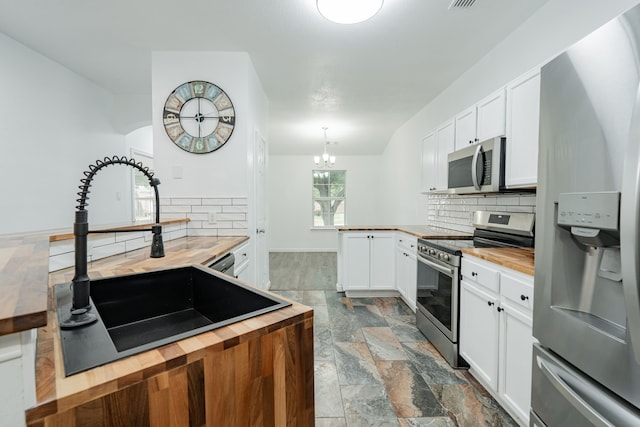 108 Freedom Trl, Forney, TX 75126 - kitchen with a peninsula, wooden counters, decorative backsplash, and appliances with stainless steel finishes