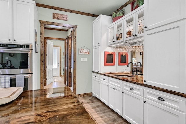 650 Scoggins Rd, Tioga, TX 76271 - kitchen featuring stainless steel double oven, a sink, light wood finished floors, and white cabinetry