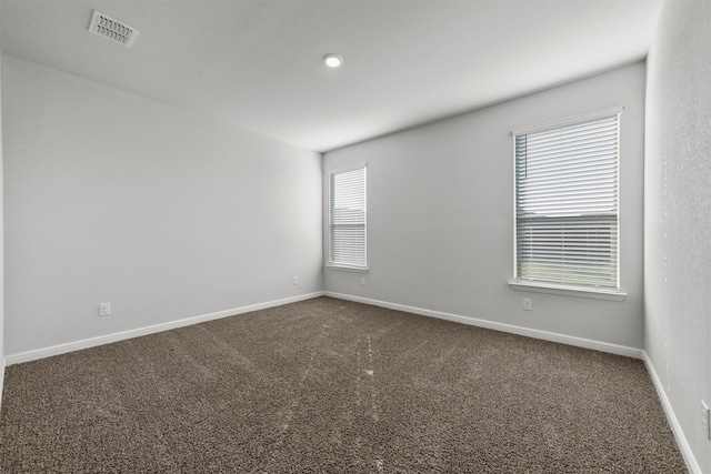 empty room with carpet floors, baseboards, and visible vents