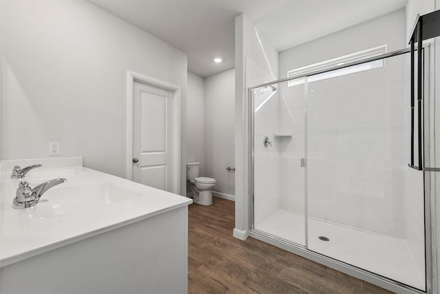 bathroom with a sink, toilet, a shower stall, and wood finished floors