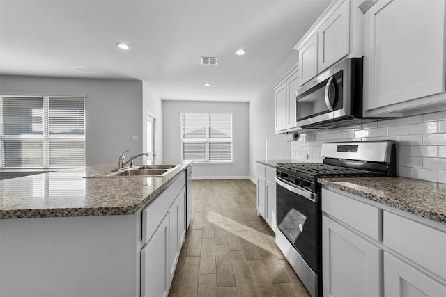 kitchen featuring a sink, wood finished floors, visible vents, baseboards, and appliances with stainless steel finishes
