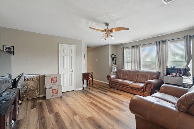 living room featuring baseboards, ceiling fan, and wood finished floors