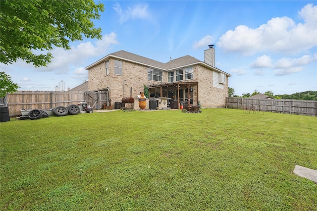 back of property featuring brick siding, a yard, a chimney, and a fenced backyard