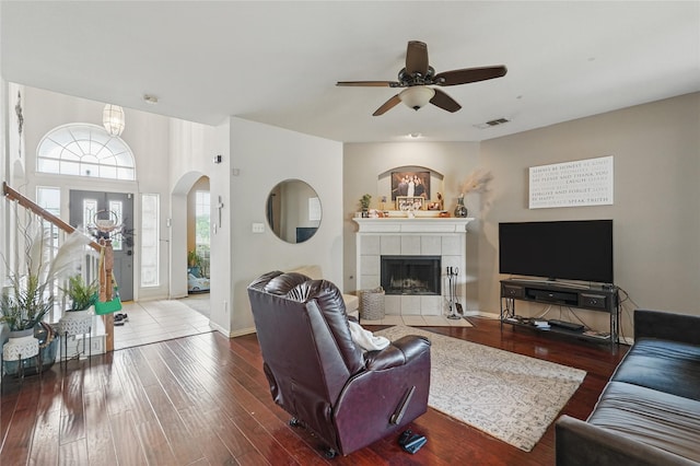 living area with a ceiling fan, visible vents, wood finished floors, arched walkways, and a fireplace