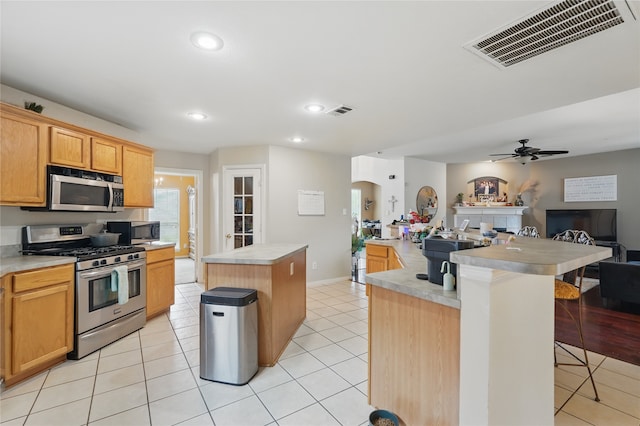 kitchen with open floor plan, a center island with sink, visible vents, and appliances with stainless steel finishes