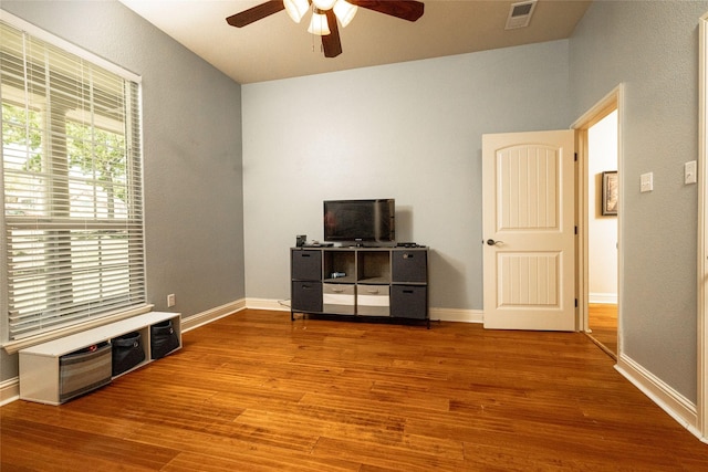 interior space with baseboards, a ceiling fan, visible vents, and wood finished floors