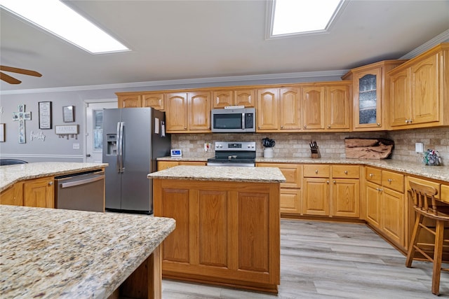 425 County Road 32230, Sumner, TX 75486 - kitchen featuring appliances with stainless steel finishes, crown molding, a ceiling fan, a kitchen island, and light stone countertops
