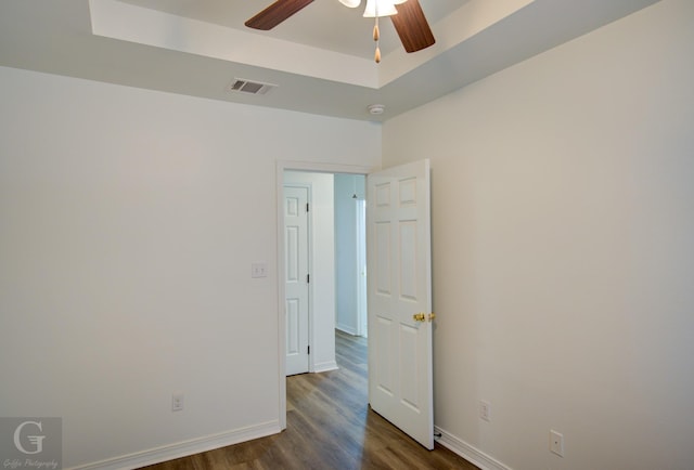 spare room featuring baseboards, dark wood-style floors, a ceiling fan, and visible vents
