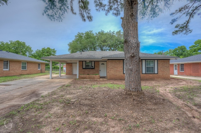 ranch-style home with concrete driveway, brick siding, and a carport