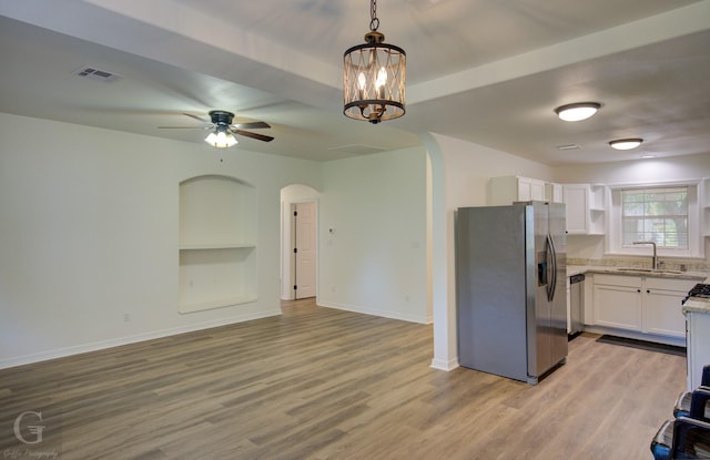kitchen featuring a sink, stainless steel appliances, visible vents, open floor plan, and arched walkways