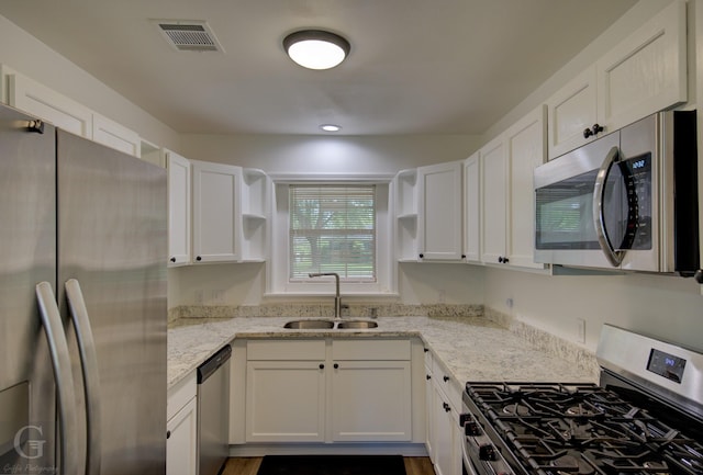 kitchen with white cabinetry, open shelves, appliances with stainless steel finishes, and a sink