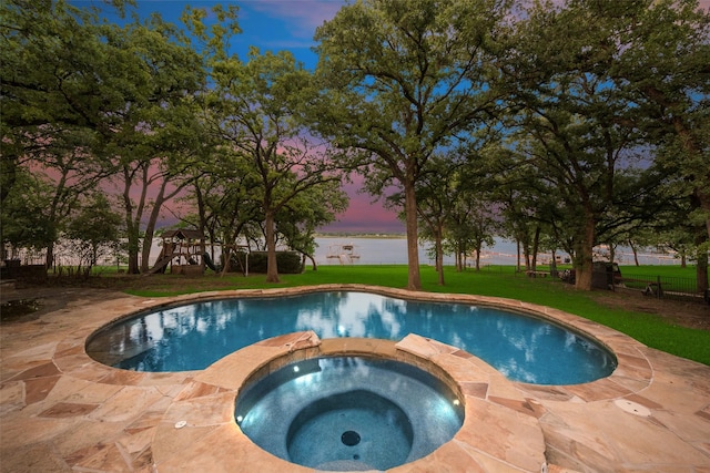 view of pool with a pool with connected hot tub, a water view, and a lawn