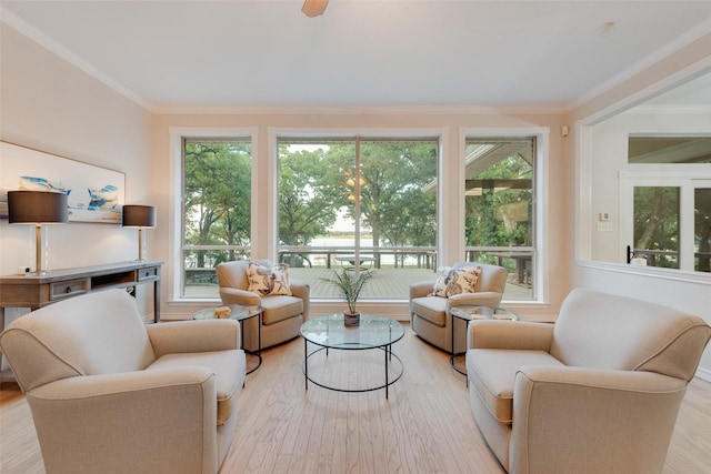 living area with crown molding, plenty of natural light, and light wood-style floors