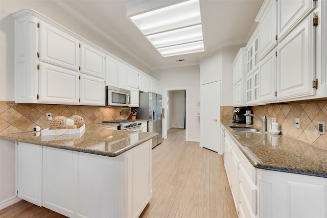kitchen featuring stone countertops, appliances with stainless steel finishes, white cabinetry, and a sink