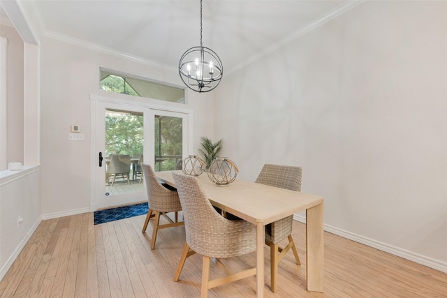 dining room with light wood finished floors, ornamental molding, a notable chandelier, and baseboards