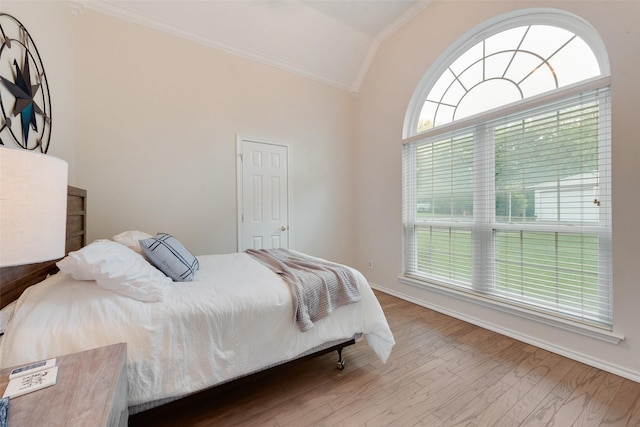 bedroom featuring lofted ceiling, baseboards, crown molding, and wood finished floors