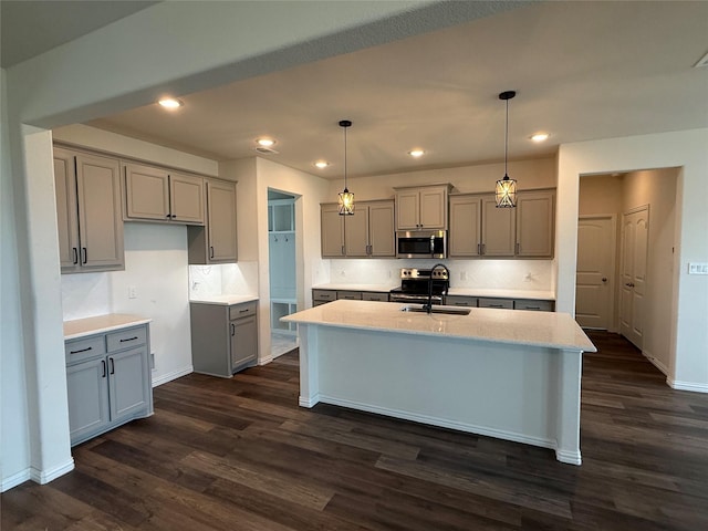 kitchen with a sink, appliances with stainless steel finishes, gray cabinetry, and dark wood-type flooring